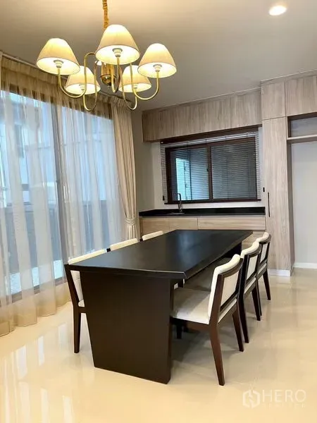 Detached House for rent in Bang Kapi, Bangkok - Dining area with six-seat table, chandelier and built-in cabinetry.