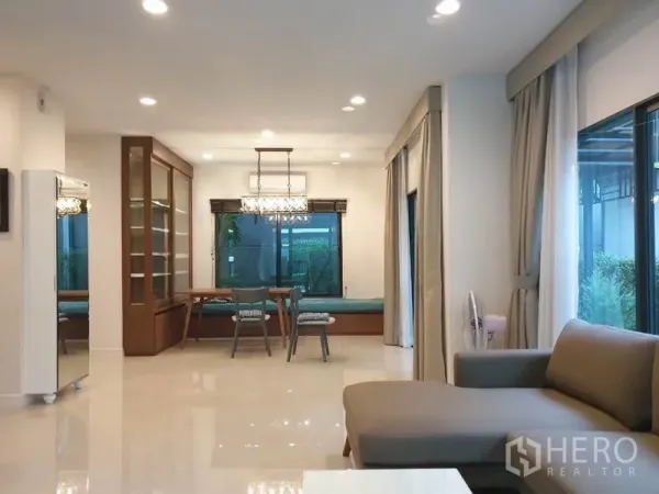 บ้าน ให้เช่าในBang Kapi, Bangkok - ห้องนั่งเล่นโปร่งสว่าง หน้าต่างบานใหญ่ ไฟดาวน์ไลท์ และโซฟาเชื่อมต่อส่วนรับประทานอาหาร.