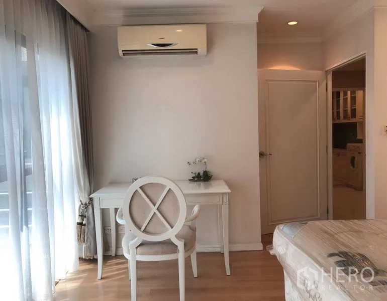 公寓 出租或出售在Sathon, Bangkok - 卧室一角的书桌区，纱帘与木地板采光明亮。