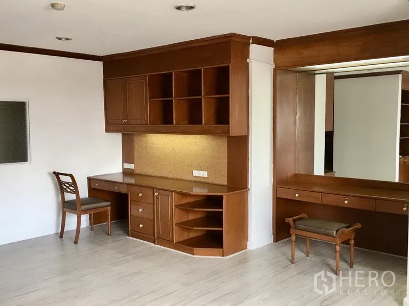 Condominium for rent in Watthana, Bangkok - Bedroom corner with built-in wooden study desk, shelving, large mirror and dressing table.
