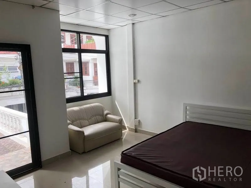 ทาวน์เฮาส์ ให้เช่าในWatthana, Bangkok - ห้องนอนสว่าง มีหน้าต่างบานใหญ่ โซฟาตัวเล็ก และทางออกสู่ระเบียง