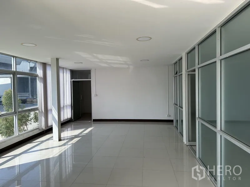 Warehouse for rent in Samut Prakan - Bright glass-partitioned office room with tiled floors and large windows.