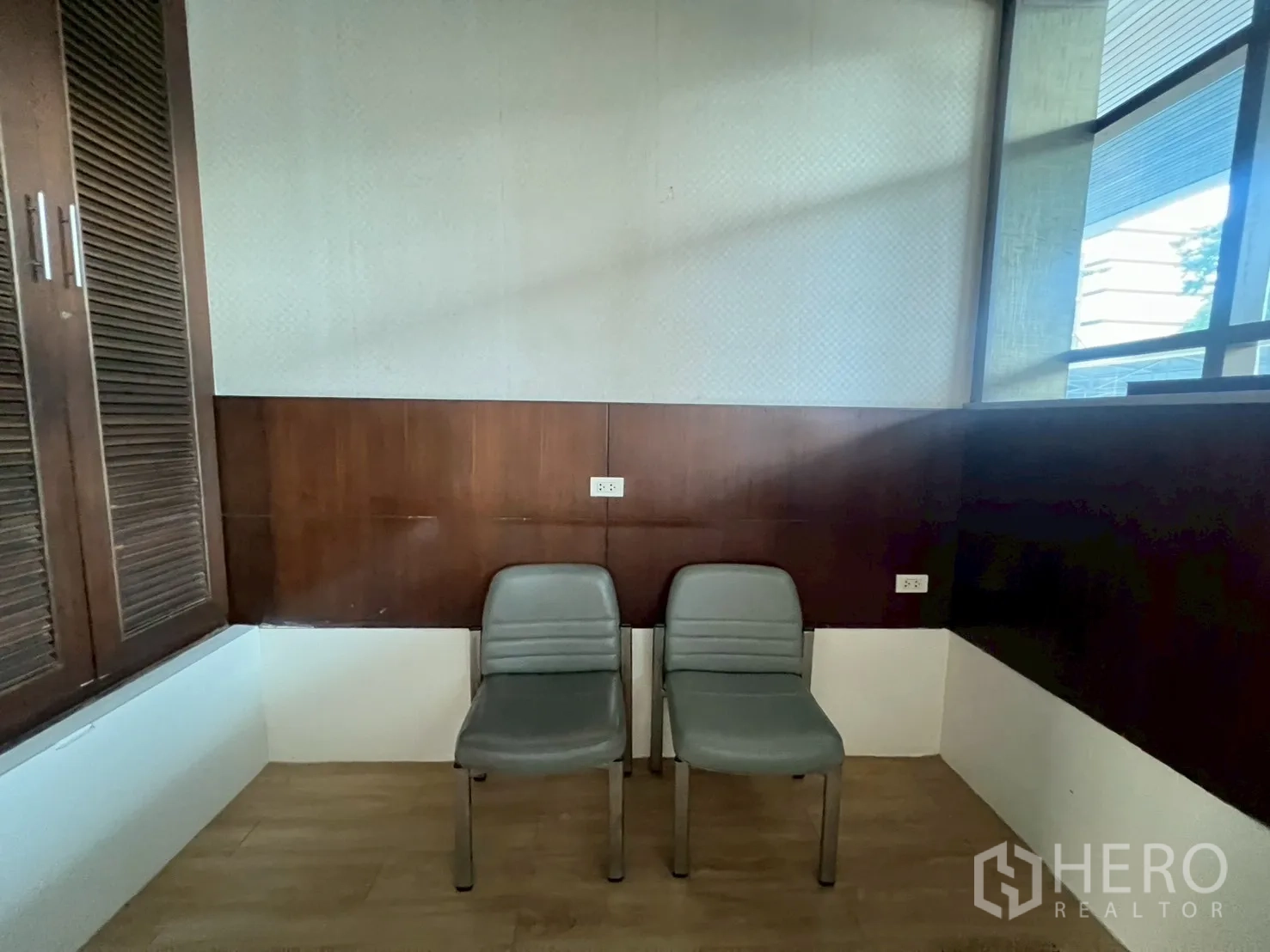 พื้นที่ขายปลีก ให้เช่า - มุมเล็กพร้อมผนังไม้ ช่องเก็บของ และเก้าอี้สองตัวใกล้หน้าต่าง