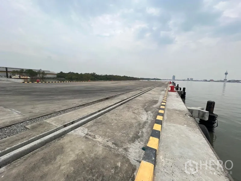 Warehouse for rent in Phra Samut Chedi, Samut Prakan - Riverside quay inside the estate with bollards and a track along the pier.