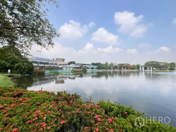 Detached House for rent - Community lake with waterfront clubhouse, landscaped flowers and blue sky reflections.