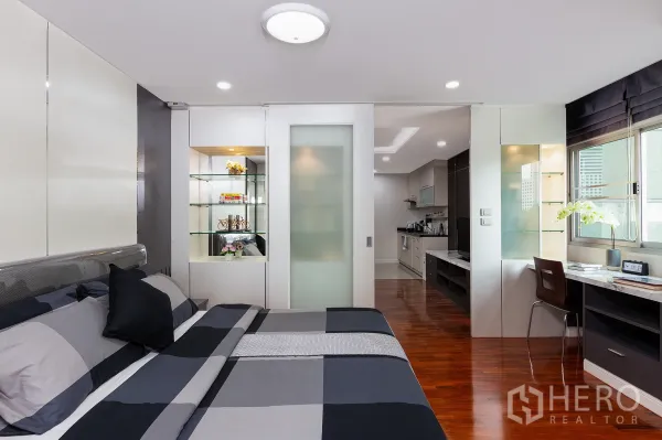 อพาร์ทเมนท์ ให้เช่าในRatchathewi, Bangkok - ห้องนอนสไตล์โมเดิร์น มีชั้นโชว์ โต๊ะทำงาน และประตูกระจกบานเลื่อนสู่ครัว พื้นไม้เงางาม
