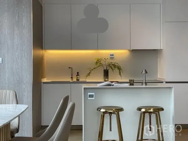 公寓 出租在Watthana, Bangkok - 现代一体化厨房，白色橱柜、灯带照明与大理石岛台配金色吧椅。