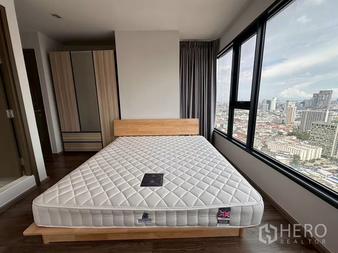 คอนโด ให้เช่าในChatuchak, Bangkok - ห้องนอนพร้อมหน้าต่างวิวเมือง เตียงไม้ และตู้เสื้อผ้า