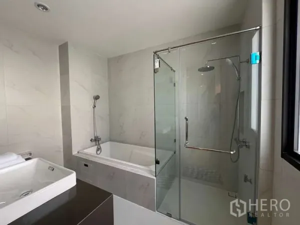 Detached House for sale in Saphan Sung, Bangkok - Contemporary bathroom with bathtub, glass-enclosed rain shower and marble-style tiles.
