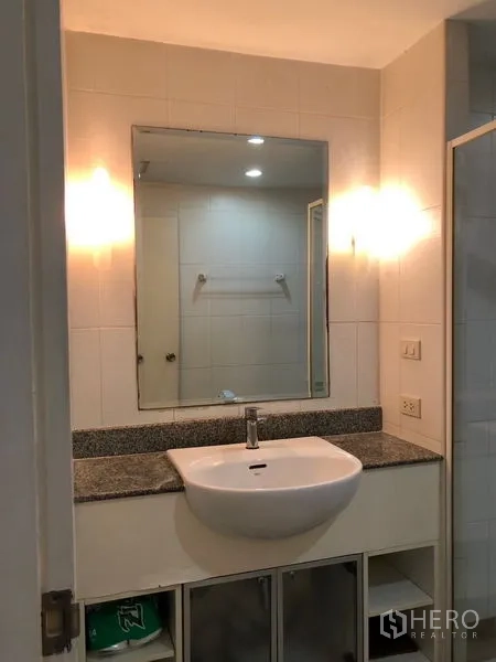 Condominium for rent or sale in Watthana, Bangkok - Bathroom vanity with large mirror, granite countertop, and under-sink storage in a Bangkok condominium.