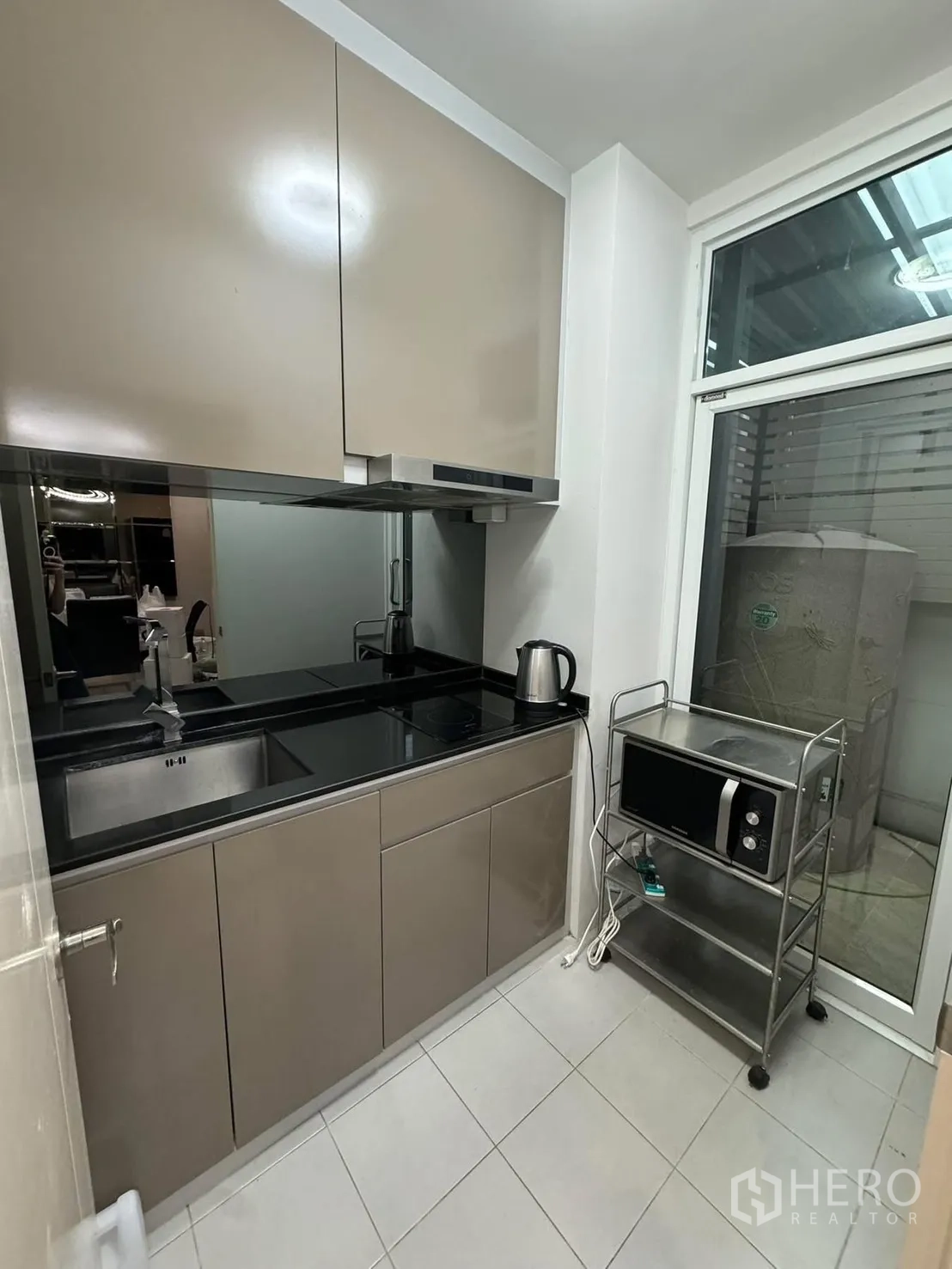 联排别墅 for rent in Suan Luang, Bangkok - 紧凑现代厨房，亮面橱柜、黑色台面，窗户通向生活区。