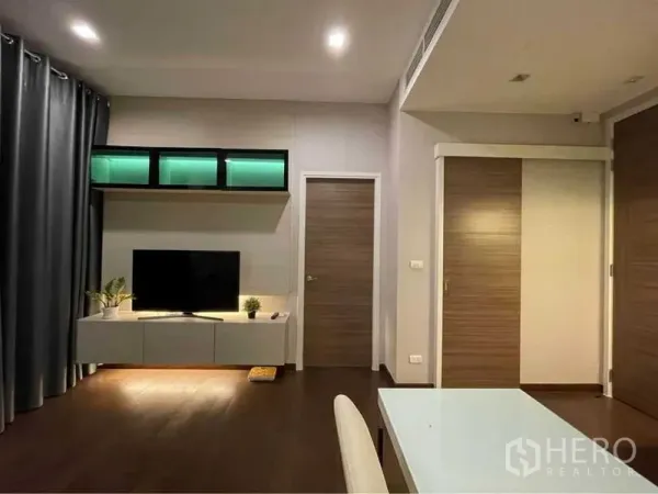 คอนโด ให้เช่าในRatchathewi, Bangkok - ห้องนั่งเล่นโมเดิร์นพร้อมชั้นวางทีวี ไฟตกแต่ง และประตูไม้