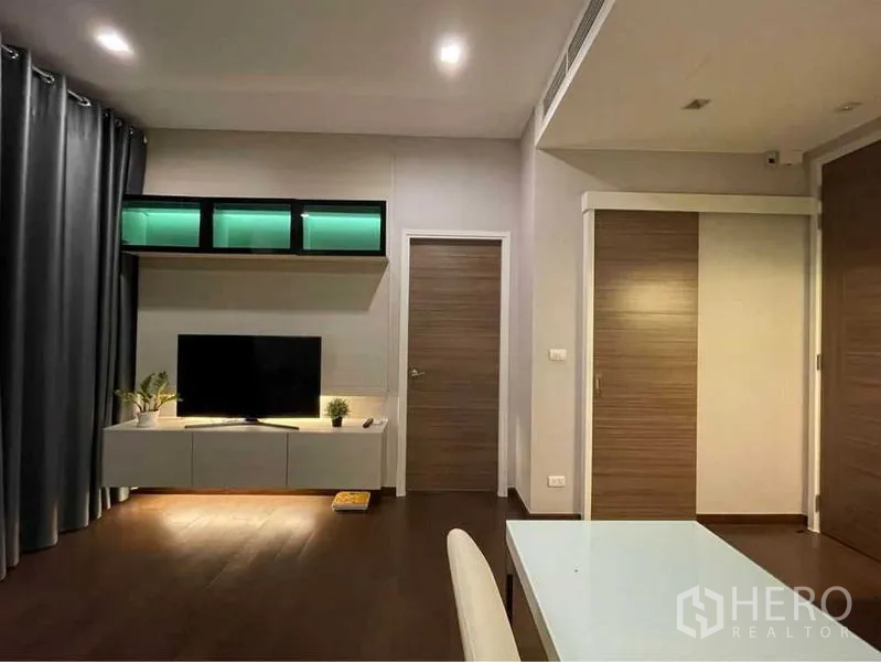 คอนโด ให้เช่าในRatchathewi, Bangkok - ห้องนั่งเล่นโมเดิร์นพร้อมชั้นวางทีวี ไฟตกแต่ง และประตูไม้