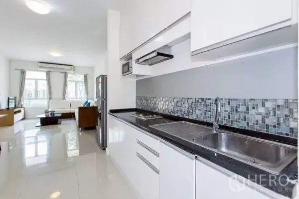 Townhouse for rent in Watthana, Bangkok - Modern linear kitchen with white cabinetry, mosaic backsplash and double sink.