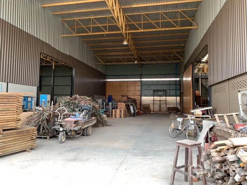 Home Office for rent in Lam Luk Ka, Pathum Thani - Covered storage bay with high rolling doors and materials stacked inside.