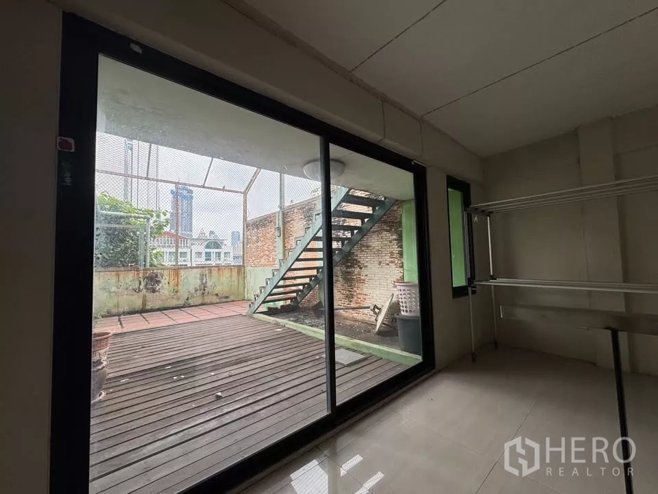 店屋 出租在Bang Rak, Bangkok - 推拉玻璃门通向铺木地的露台和室外楼梯。