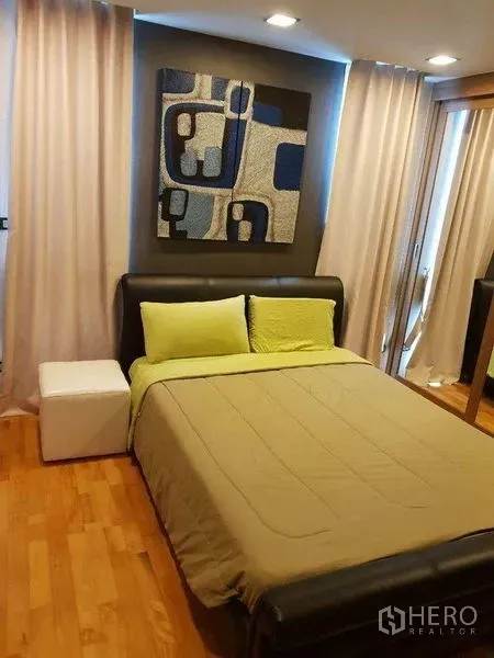 Condominium for sale in Bang Rak, Bangkok - Cozy bedroom with artwork, curtains and upholstered bed at Quad Silom.
