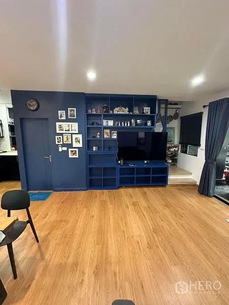 ทาวน์เฮาส์ ขายในWang Thonglang, Bangkok - ห้องนั่งเล่นพร้อมชั้นทีวีบิวท์อินสีน้ำเงินและพื้นไม้โทนอุ่น