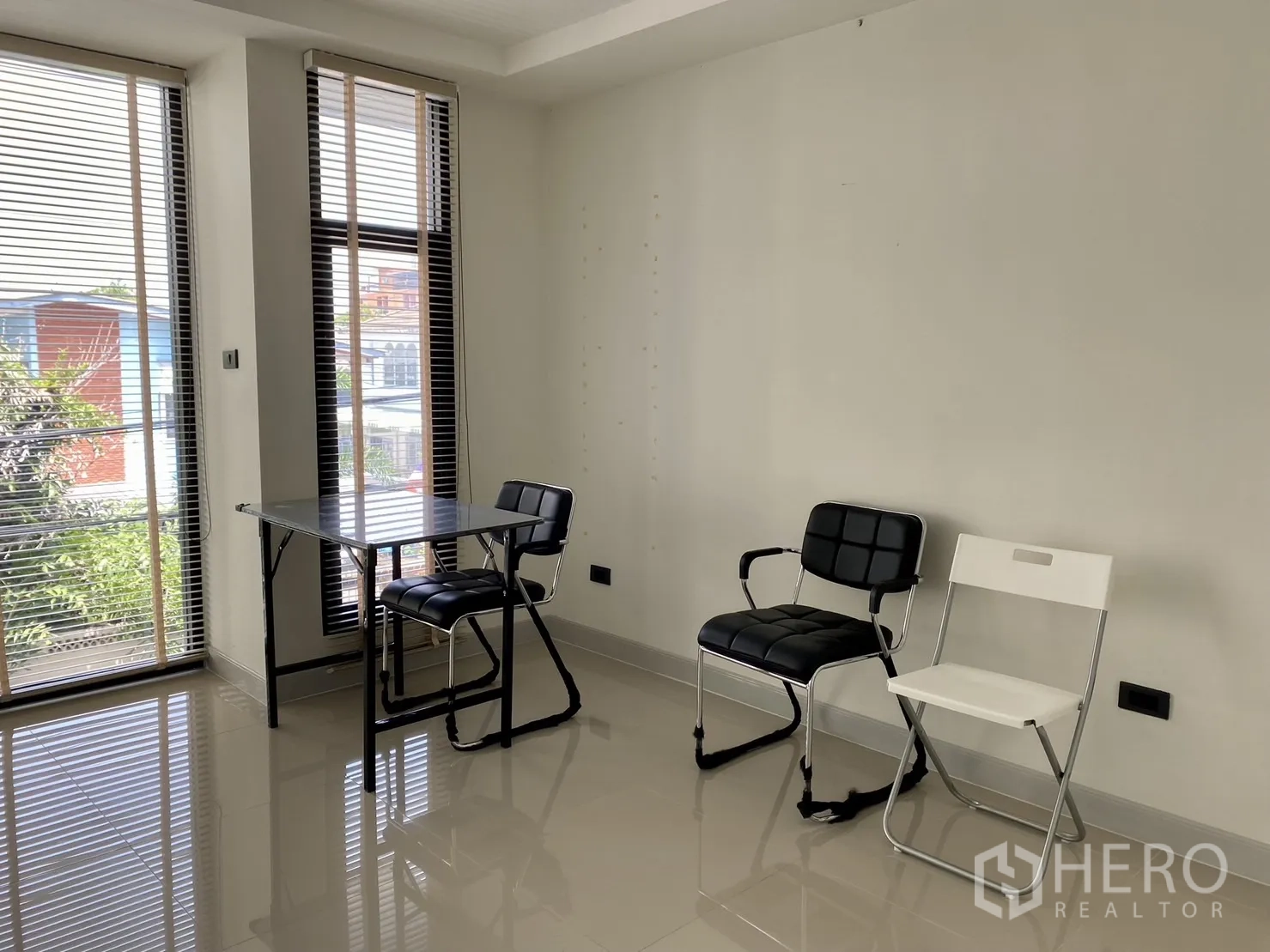 Home Office for rent or sale in Phra Khanong, Bangkok - Bright corner room with floor-to-ceiling windows and blinds, simple chairs and glossy tile floor.