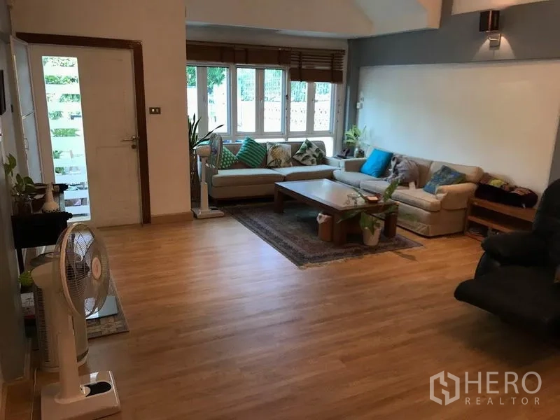 ทาวน์เฮาส์ ให้เช่าหรือขายในKhlong Toei, Bangkok - ห้องนั่งเล่นสว่างด้วยหน้าต่างบานใหญ่ พื้นไม้ และโซฟาเข้ามุม
