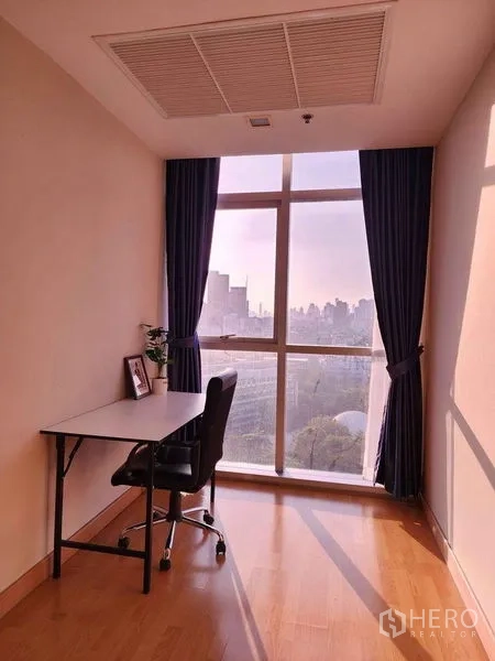 Condominium for rent in Khlong Toei, Bangkok - Work-from-home nook with desk and chair beside a large window overlooking the city.