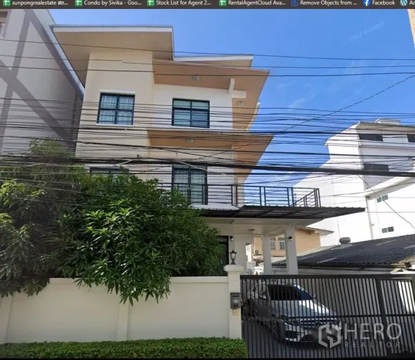 独立式住宅 出售在Phra Khanong, Bangkok - 房屋正立面，带有车棚、滑动铁门与成熟绿化。