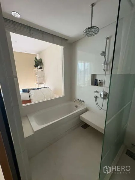 Condominium for rent - Modern bathroom with bathtub, glass-enclosed rain shower and a window to the bedroom.