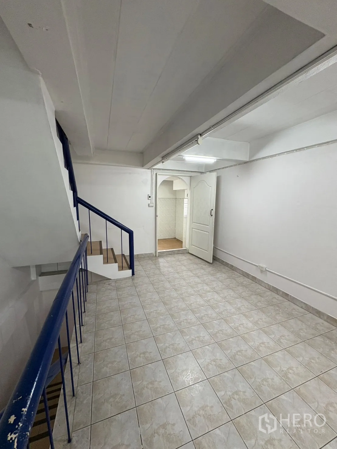 店屋 出租在Phra Khanong, Bangkok - 楼梯旁瓷砖走廊，通往另一功能房间的门。