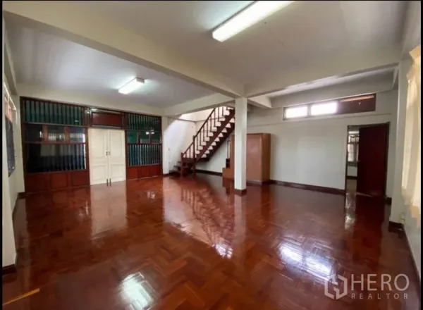 Home Office for rent in Suan Luang, Bangkok - Large open-plan hall with glossy parquet floors and a wooden staircase, perfect for workspace or showroom use.