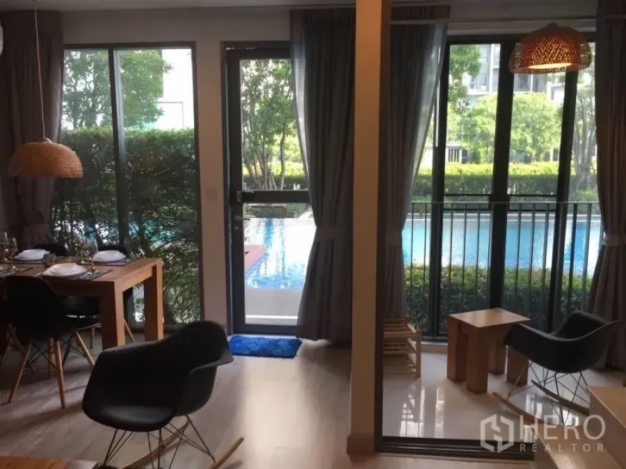 Condominium for rent in Phra Khanong, Bangkok - Living and dining area with floor-to-ceiling windows opening to pool and garden view