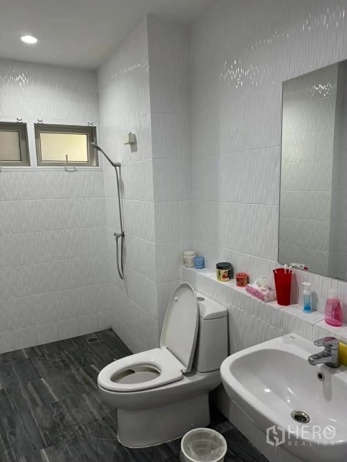 Detached House for rent in Watthana, Bangkok - White-tiled bathroom with handheld shower, toilet, and sink.