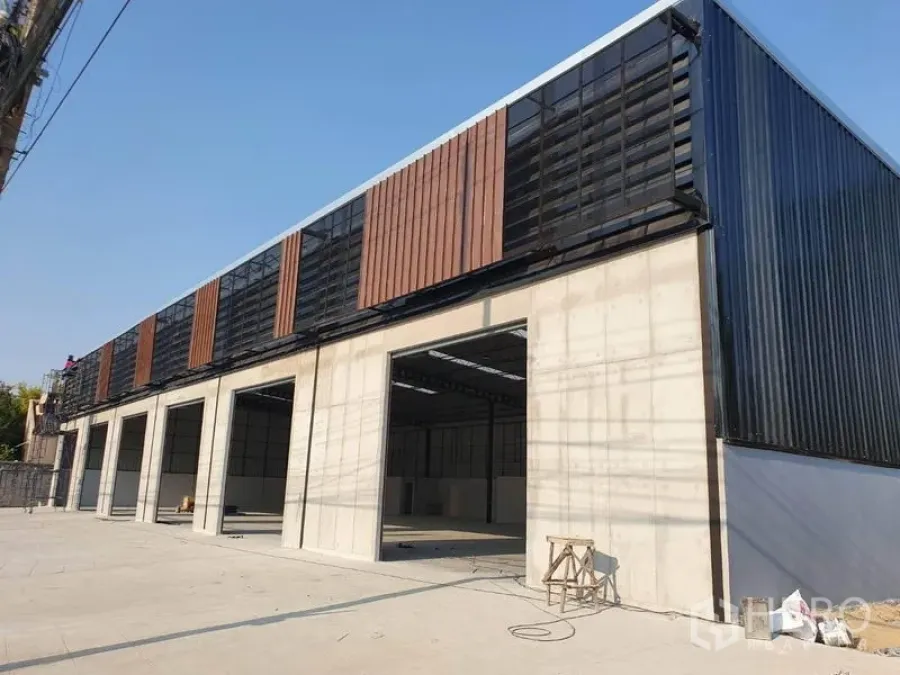 Warehouse for rent in Nonthaburi - Modern warehouse exterior in Pak Kret with multiple large loading bays and ventilated facade panels.