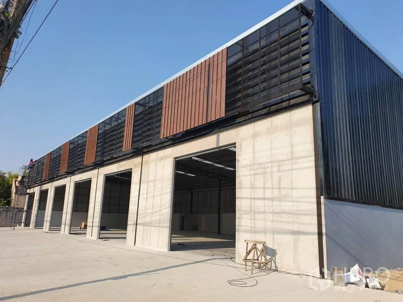 Warehouse for rent in Nonthaburi - Modern warehouse exterior in Pak Kret with multiple large loading bays and ventilated facade panels.