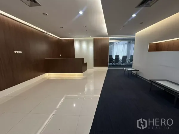 Office Space for rent in Watthana, Bangkok - Alternate view of the reception lobby showing a wood front desk, carpeted waiting zone and a glass-walled boardroom in the background.