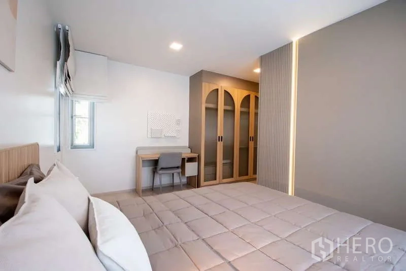 Detached House for rent in Bang Phli, Samut Prakan - Guest bedroom with bed, study desk and arched glass-door wardrobe.