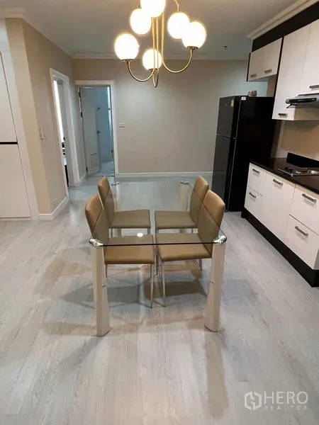 Condominium for sale in Sathon, Bangkok - Bright dining area with a glass table for four beside a modern kitchen and pendant lighting.
