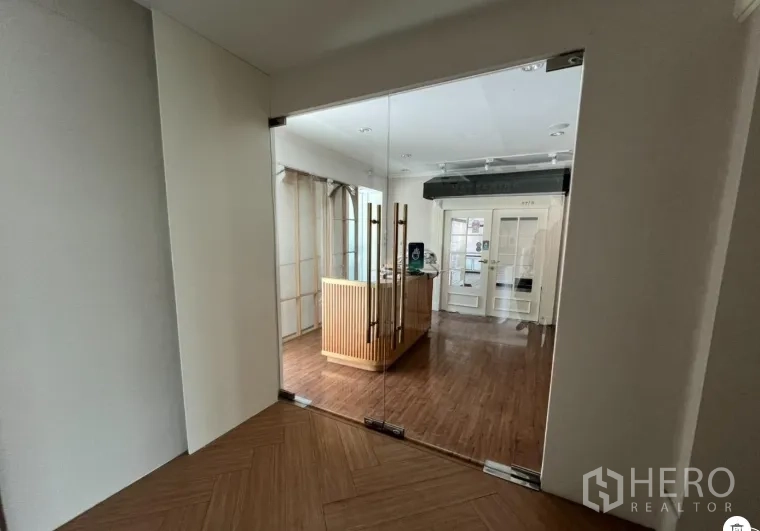 พื้นที่ขายปลีก ให้เช่า - ประตูกระจกบานคู่สู่โซนต้อนรับ เคาน์เตอร์ไม้และไฟสปอร์ตไลต์