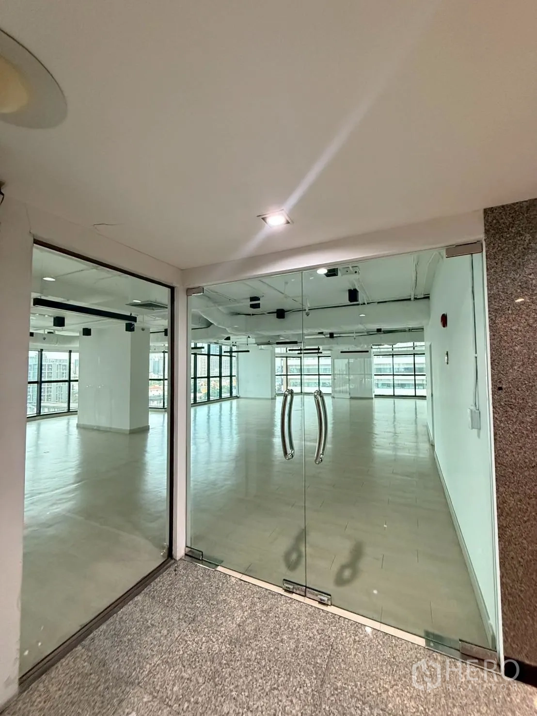 Office Space for rent in Watthana, Bangkok - Glass double doors opening to a bright open office with large windows.