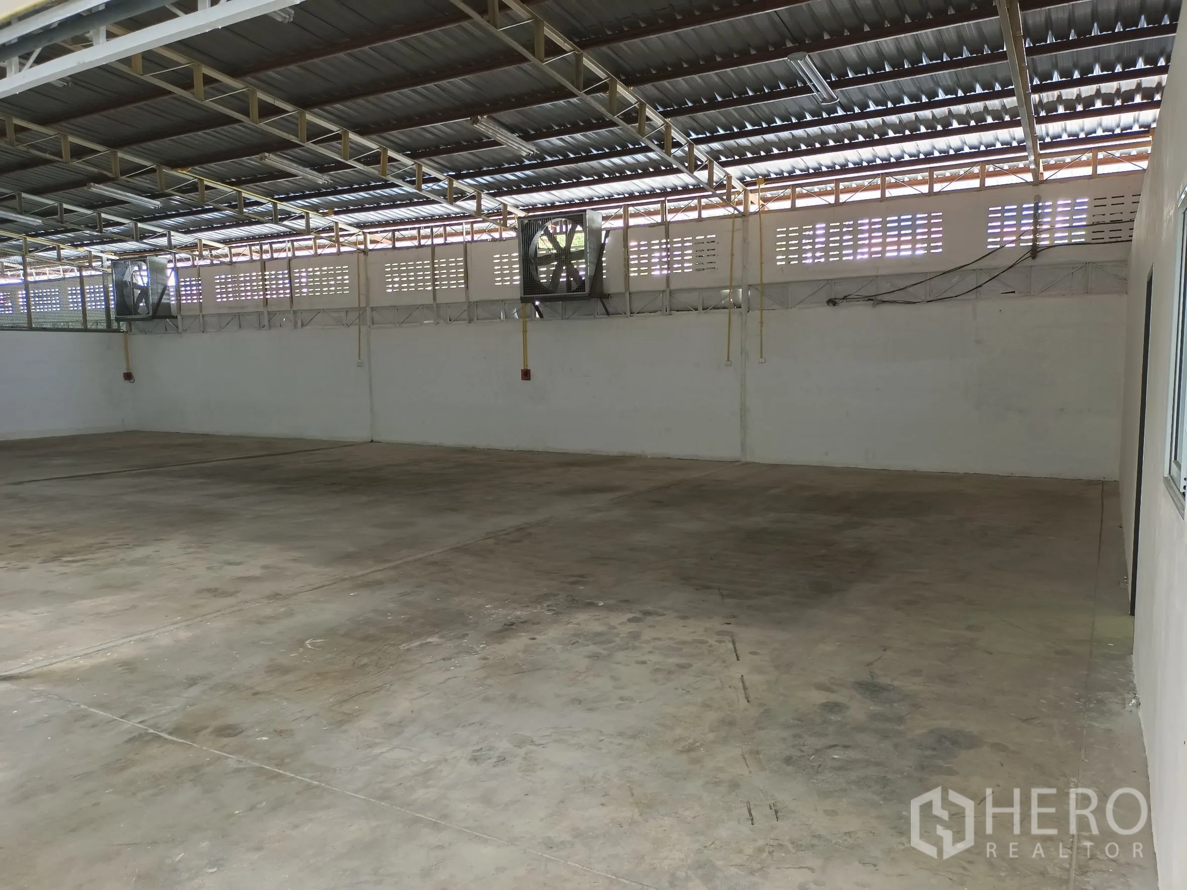 Warehouse for rent in Suan Luang, Bangkok - Wide industrial floor area with wall-mounted exhaust fans and roof skylight strips for natural light.