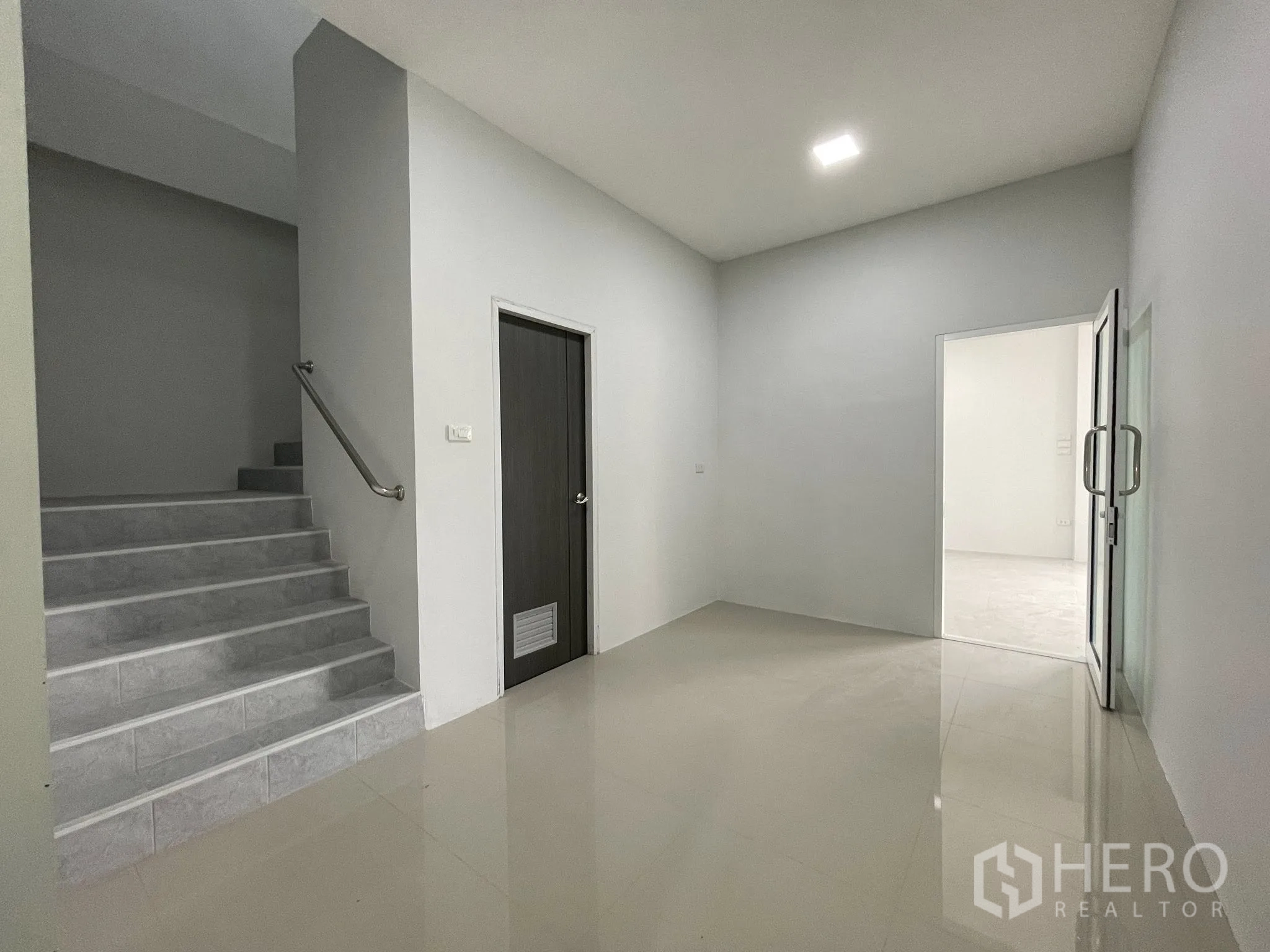 Factory for rent or sale in Bang Phli, Samut Prakan - Ground floor lobby with staircase, dark door, and glass entry to the office.
