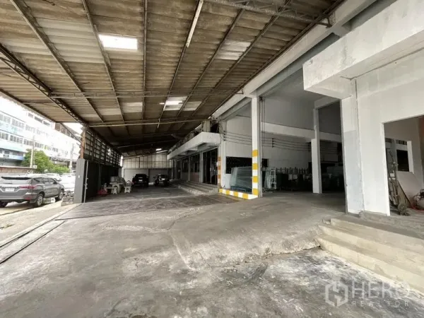 Warehouse for rent in Bang Phli, Samut Prakan - Covered driveway and parking area in front of multiple loading bays at the warehouse.