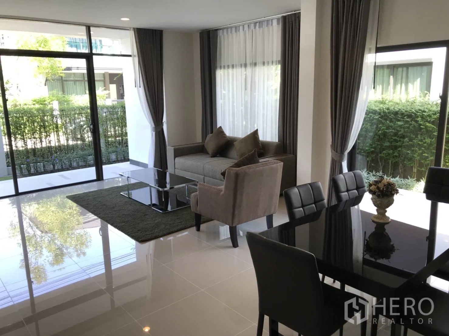 Detached House for rent in Bang Kapi, Bangkok - Open-plan lounge and dining area with glossy floors and sliding glass doors to the garden.