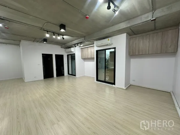 Office Space for rent in Watthana, Bangkok - Corner view showing sliding glass doors, wall-mounted cabinets and a split-type air conditioner.