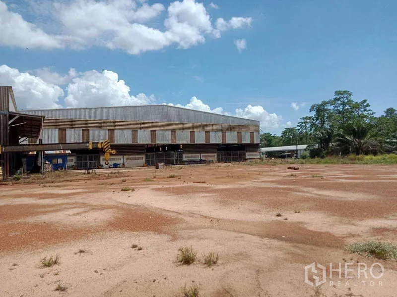 工厂 出售在Chachoengsao - 仓库外观与开阔的土场和绿化，晴空万里。