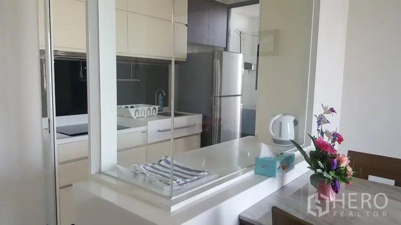 คอนโด ให้เช่าในBangkok - เคาน์เตอร์บาร์เชื่อมครัวกับพื้นที่ทานอาหาร พร้อมฉากกระจกและแจกันดอกไม้