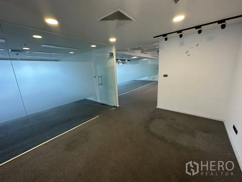 Office Space for rent - Reception or breakout area beside glass partitions and spotlights.