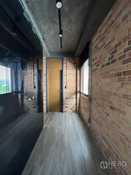 联排别墅 出租在Saphan Sung, Bangkok - 工业风过道，裸露红砖墙、轨道灯和黑色玻璃衣柜。