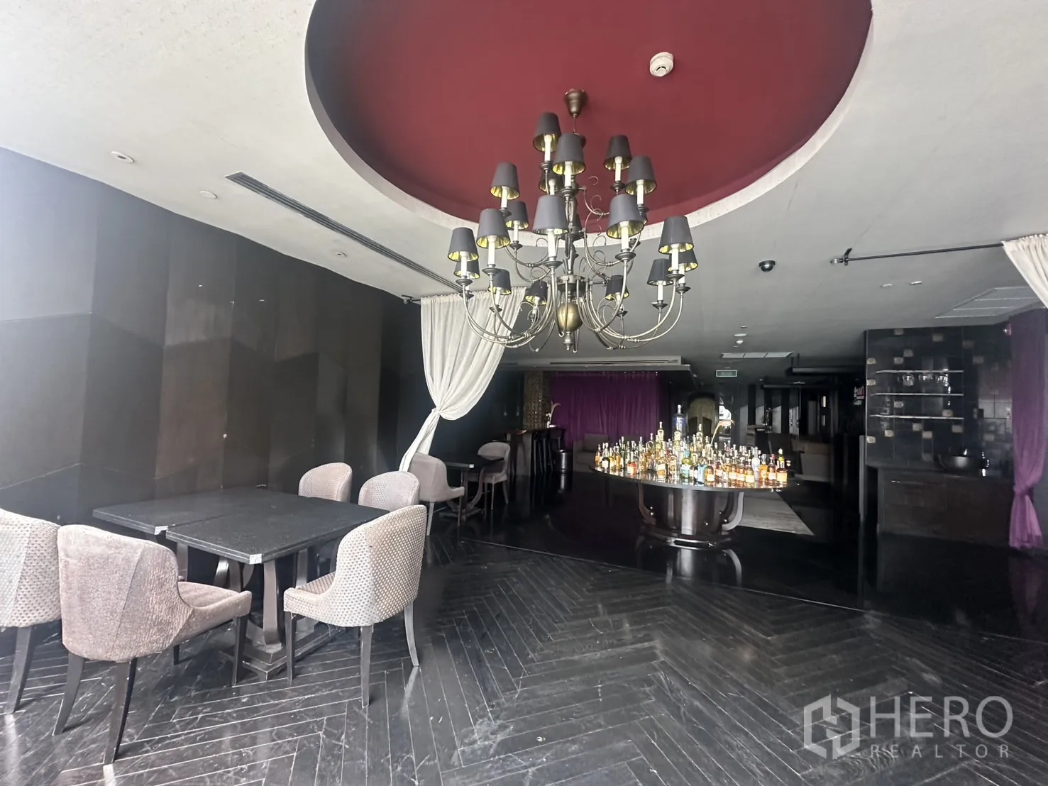 พื้นที่ขายปลีก ให้เช่าในKhlong Toei, Bangkok - มุมรับประทานอาหารพร้อมโคมระย้า ผ้าม่าน และโต๊ะรอบจุดโชว์ขวด