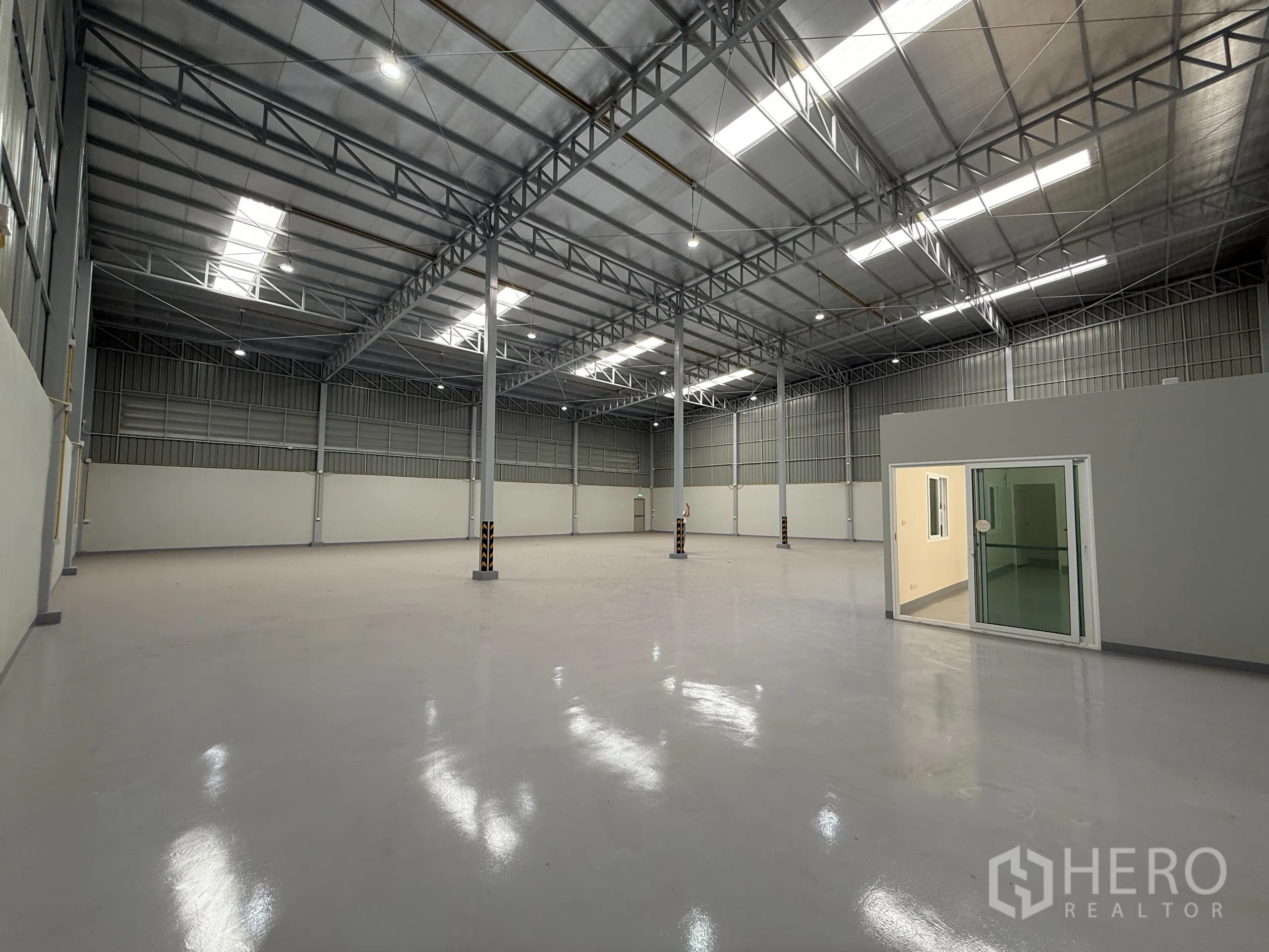 货栈 出租在Bang Khen, Bangkok - 仓库内部高挑钢结构屋顶，采光天窗与LED照明，亮面环氧地坪，带玻璃隔断办公室。