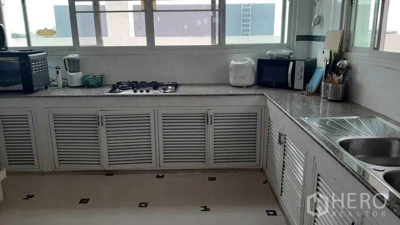 คอนโด ให้เช่าในWatthana, Bangkok - ครัวปิดสว่างไสว เคาน์เตอร์แกรนิตรูปตัวแอล เตาแก๊ส อ่างล้างจานคู่ และตู้บานเกล็ดสีขาวใต้หน้าต่างกว้าง